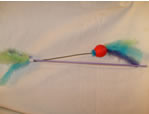 Varilla con pelota de hilo de color, cascabel y plumas